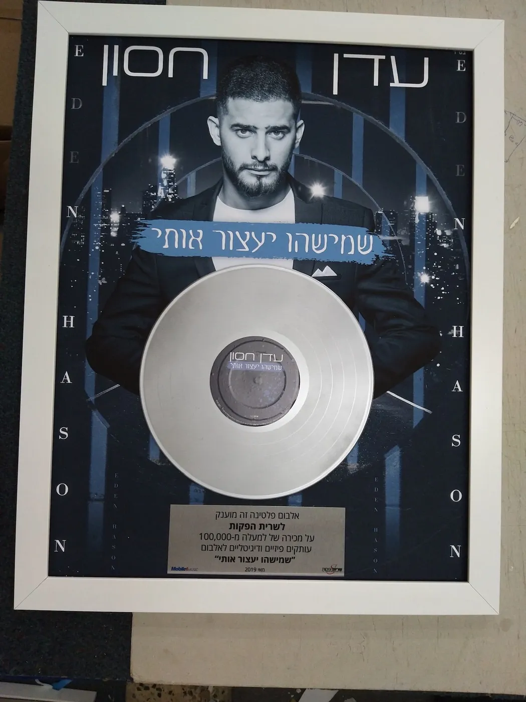 מסגור פרס אלבום פלטינה — תקליט פלטינה מקובע מעל עטיפת האלבום, במסגרת לבנה דקה